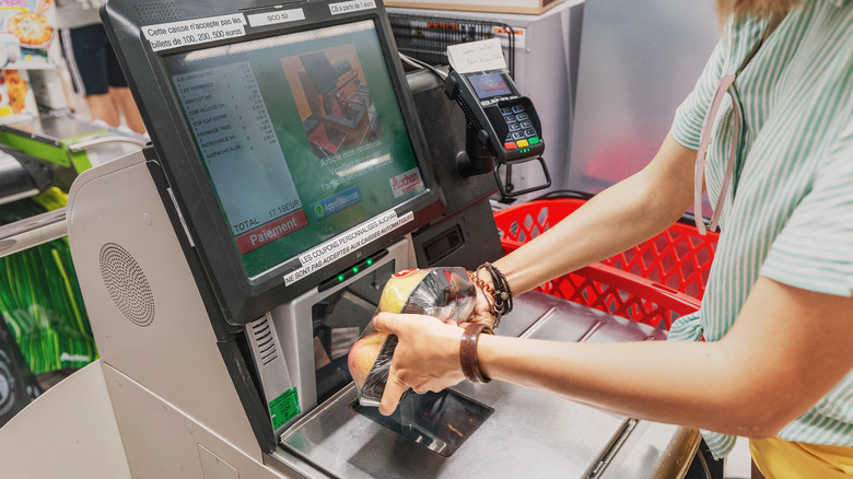 A woman scanning an item at a self-checkout machine