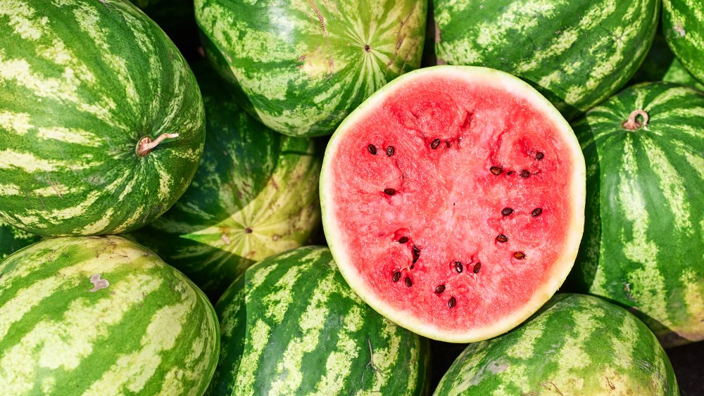 Cut ripe watermelon on top of whole watermelons