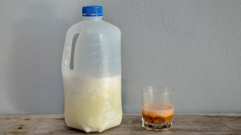 expired milk in a carton next to a glass on a tabletop