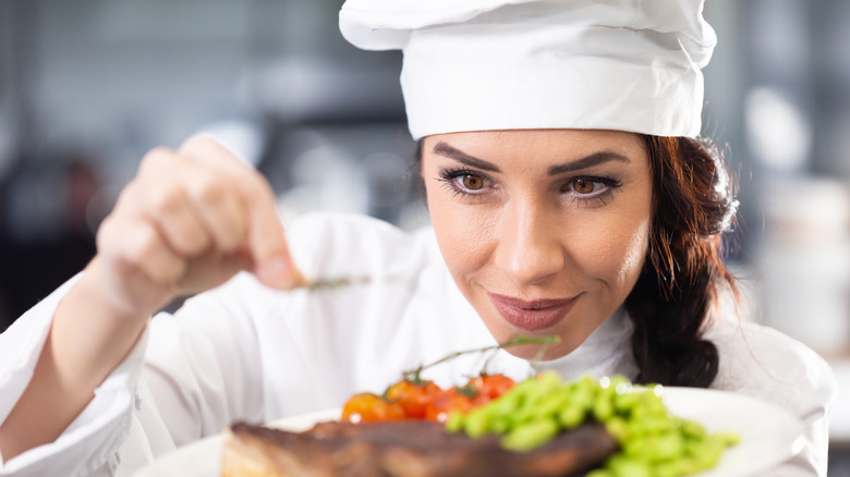 Female chef garnishing plate of food