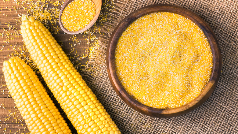 Two corn cobs and bowl of grits on wood table