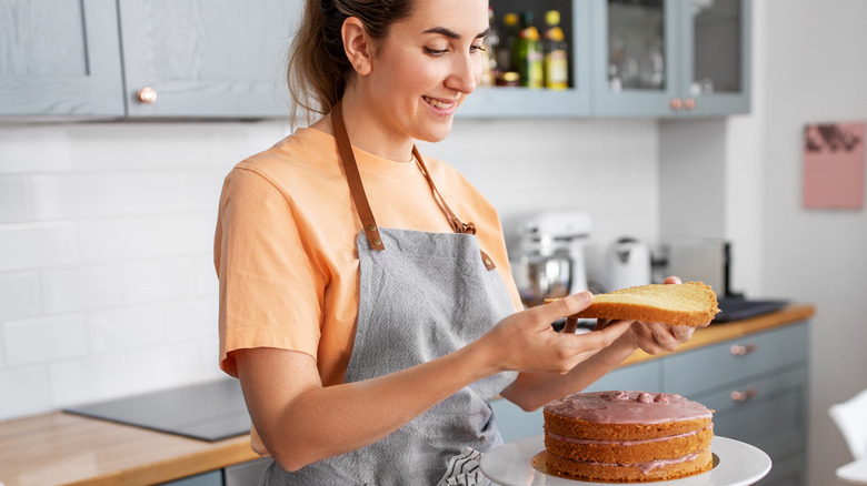 Person wearing apron assembling thin cake layers