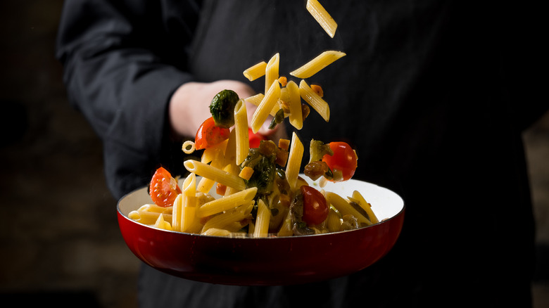 Chef tossing pasta in pan