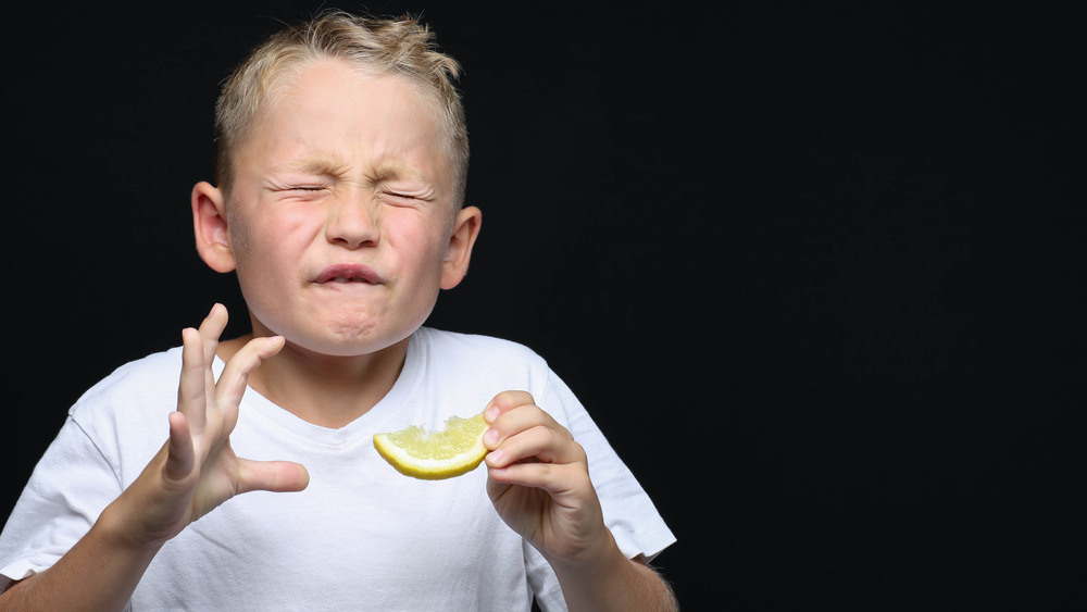Boy tasting sour lemon wedge