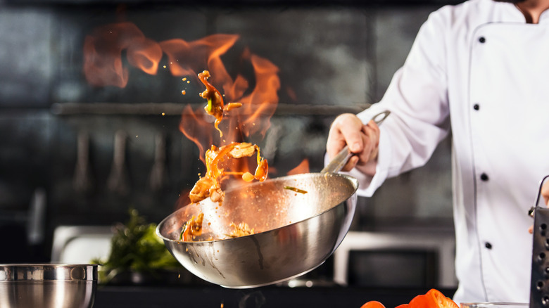 Chef tossing food in flaming wok