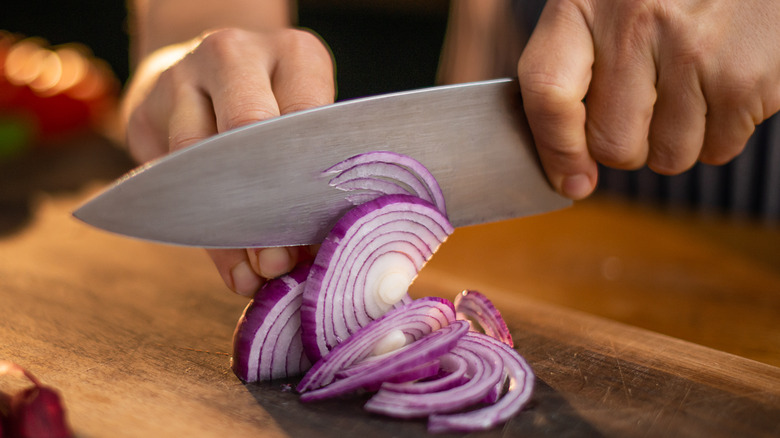 Chopping red onion on wooden cutting board