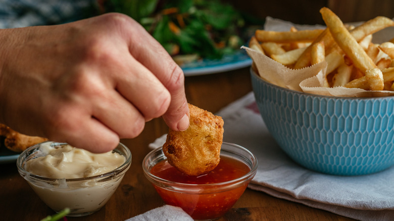 dipping chicken nugget into sauce