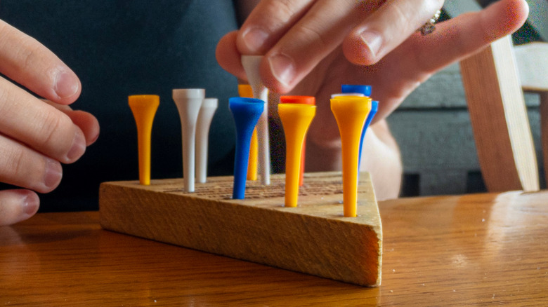 Person playing peg game on wooden table