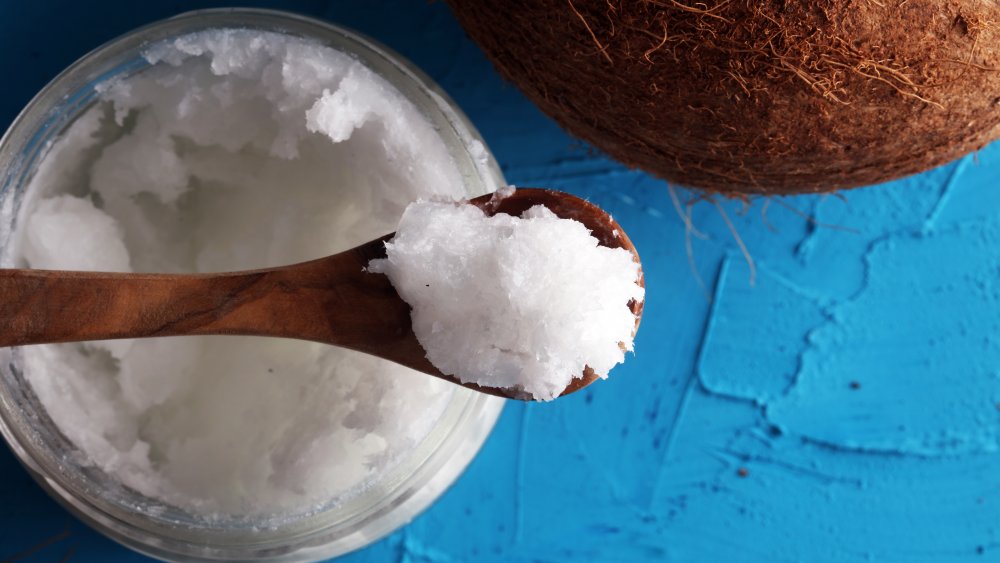 Spoonful of coconut oil next to a coconut shell
