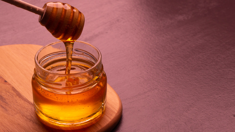 jar of honey with wooden dipper