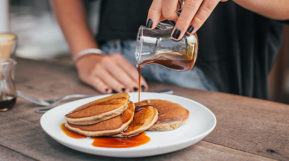 Pouring maple syrup on pancakes