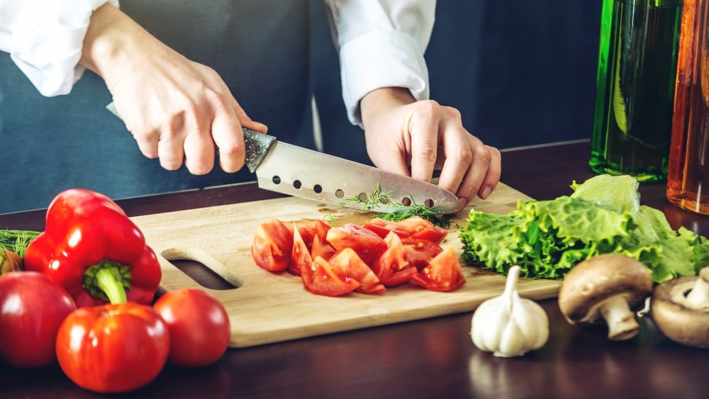 person cutting vegetables with a kitchen knife