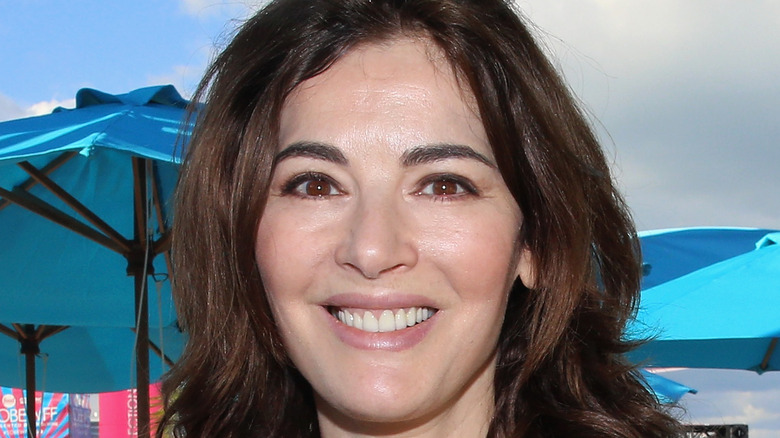 Nigella Lawson smiling in front of blue umbrellas