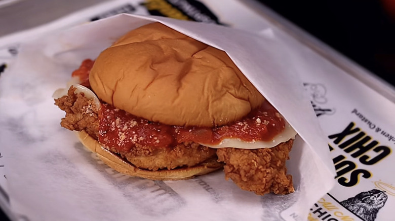 A chicken Parmesan sandwich wrapped in paper on a tray