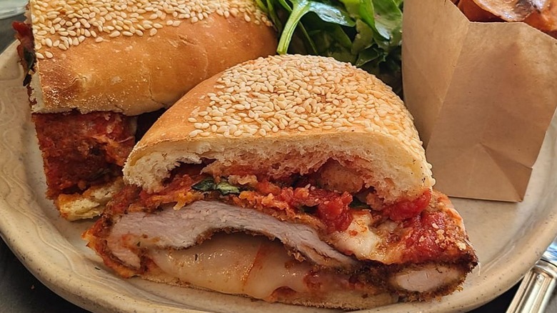 The middle view of a chicken parm sando from Esther's with a salad and chips