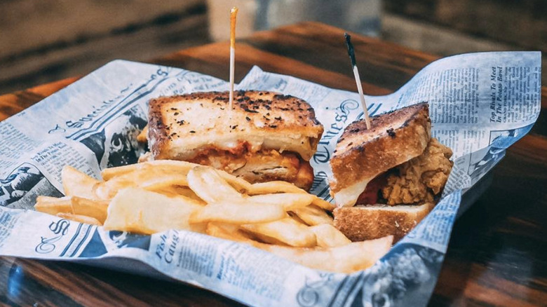The chicken Parmesan sandwich on a piece of newspaper with french fries