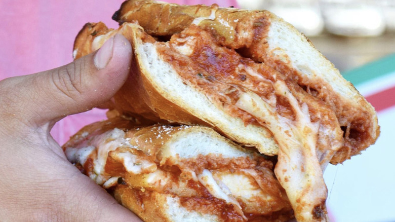 Hands holding the chicken Parmeroni sandwich from Geraldi's