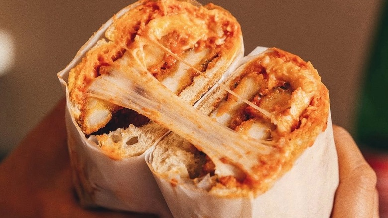 The chicken Parmesan sandwich cut in half with cheese stretched between the halves