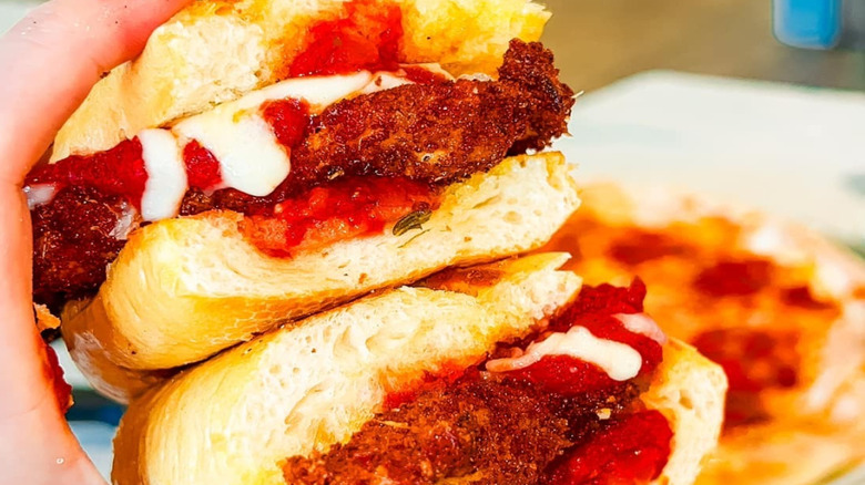 A hand holding a chicken Parmesan sandwich from DeVivos Bros. Eatery