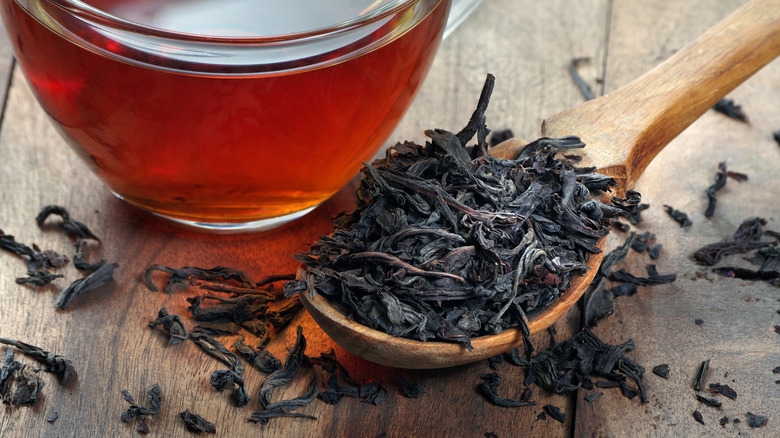 Spoonful of dried tea beside a cup of tea