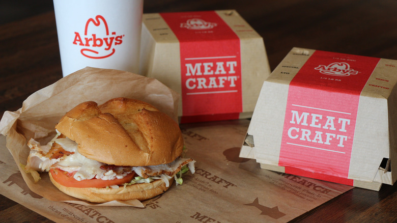 Arby's sandwich next to Arby's boxes and drink