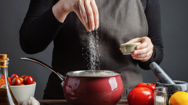 hand sprinkling salt into saucepan
