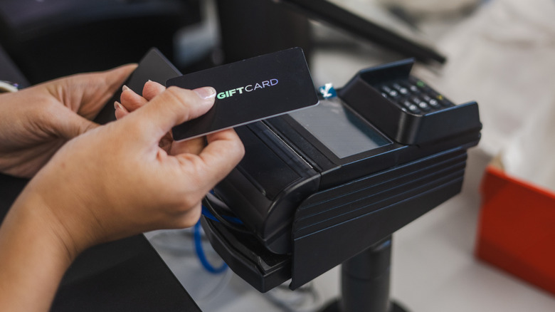 Customer holding gift card at pay station.