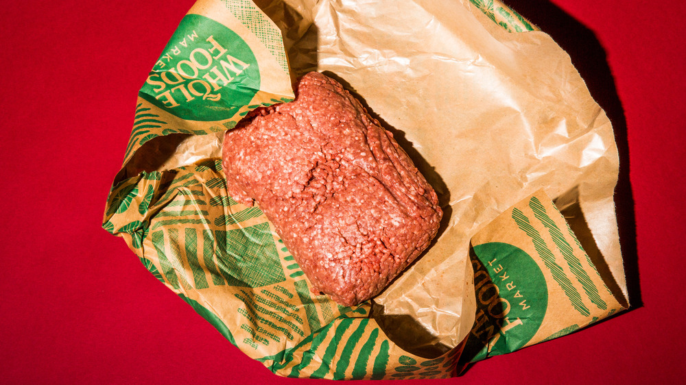 Ground beef in a brown paper wrapper on a red background