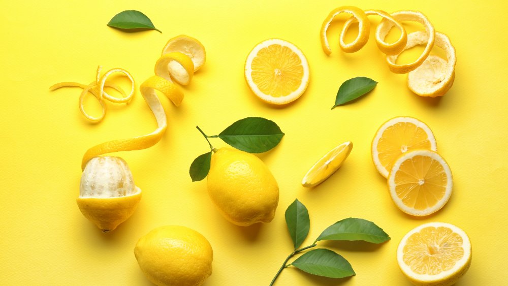 whole and peeled lemons against a yellow background