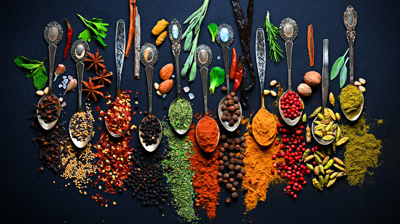 Spoons with colorful spices against a black background