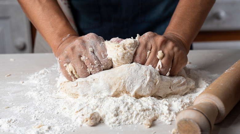 Hands kneading flour on a table