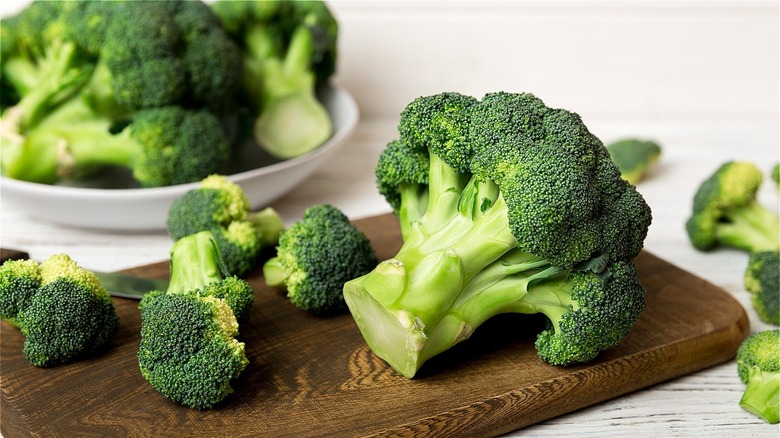 Broccoli and its florets on a wooden board