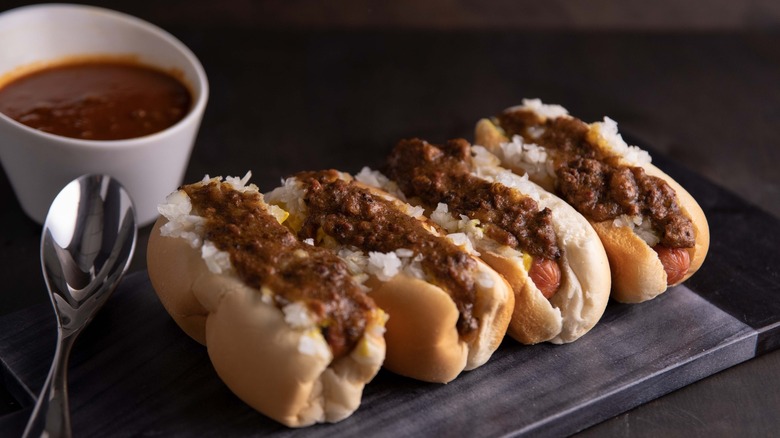 Chili dogs with onion on a wooden board