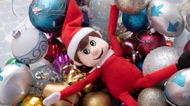 Elf on a Shelf toy playing in Christmas baubles 