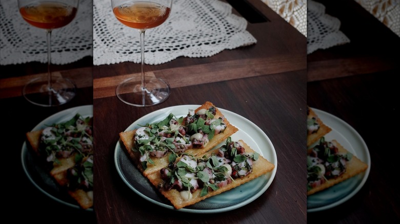 breadfruit tostones from Kabawa on a ceramic plate with a glass of wine