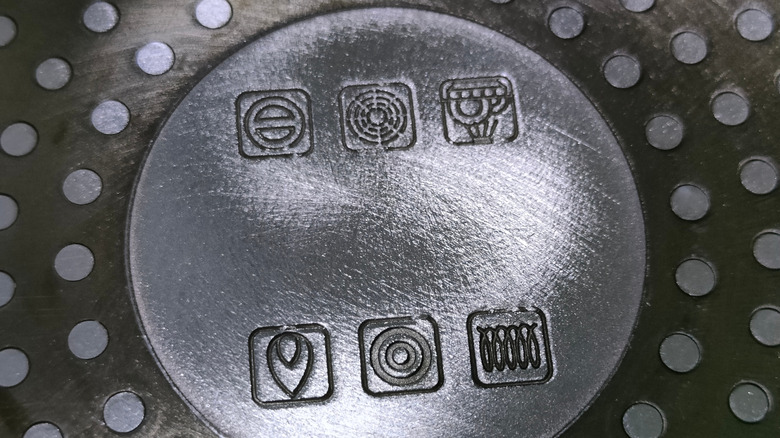 The bottom of a metal pan with instructional symbols indicating proper use and maintenance.