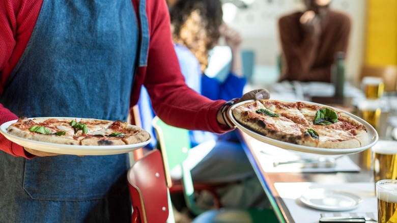 Waiter serving plates of food at restaurant