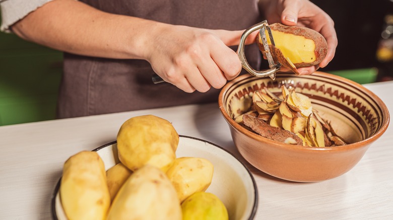 man peeling potato skins into a bowl