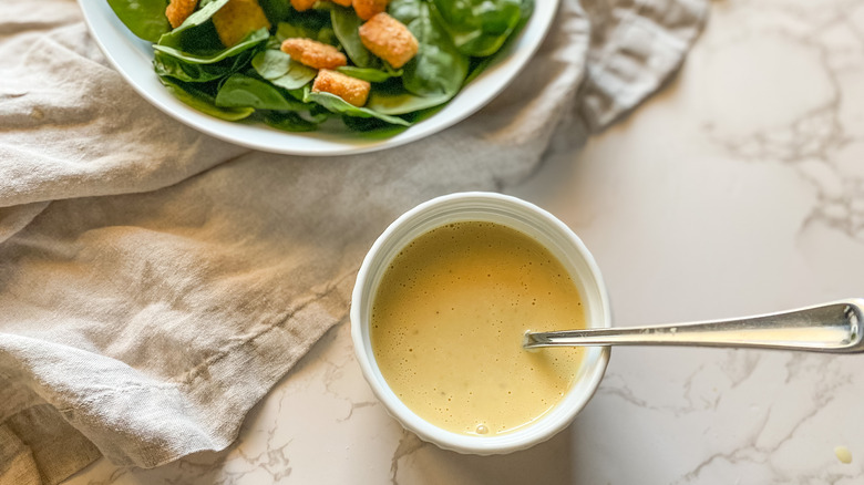 A serving of Caesar dressing in a bowl with a salad