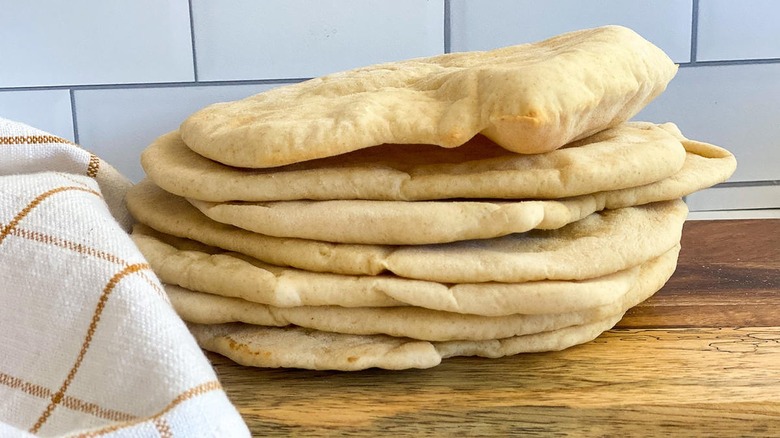 A stack of pita bread sitting on a cutting board