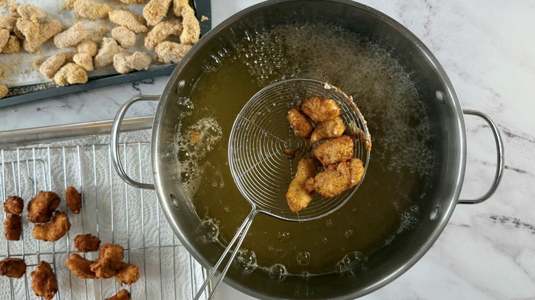 Fried cheese curds in strainer above pot of oil