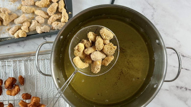 Strainer placing cheese curds into pot with oil