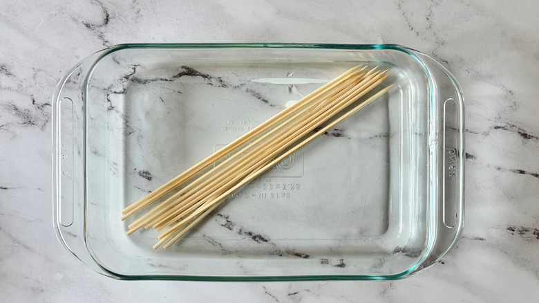 Bamboo skewers soaking in clear baking dish