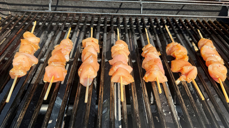 Raw chicken skewers on grill