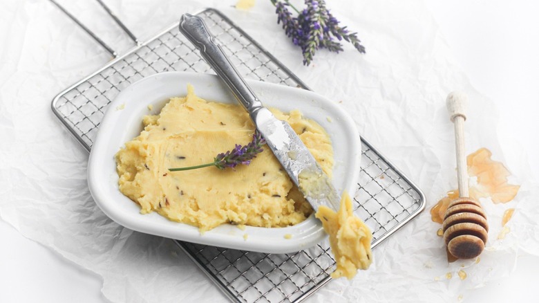 Honey lavender butter in a white butter dish on a wooden board