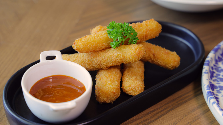 A plate of mozzarella sticks served with marinara sauce.