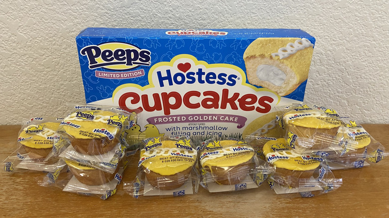 Peeps Hostess Cupcakes Frosted Golden Cake box surrounded by wrapped cupcakes on wooden surface