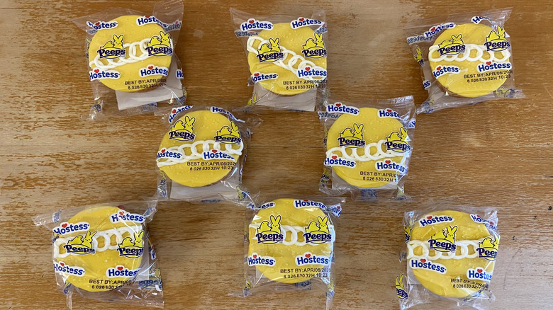 top-down view of wrapped Peeps Hostess Cupcakes on wooden surface in an alternating pattern