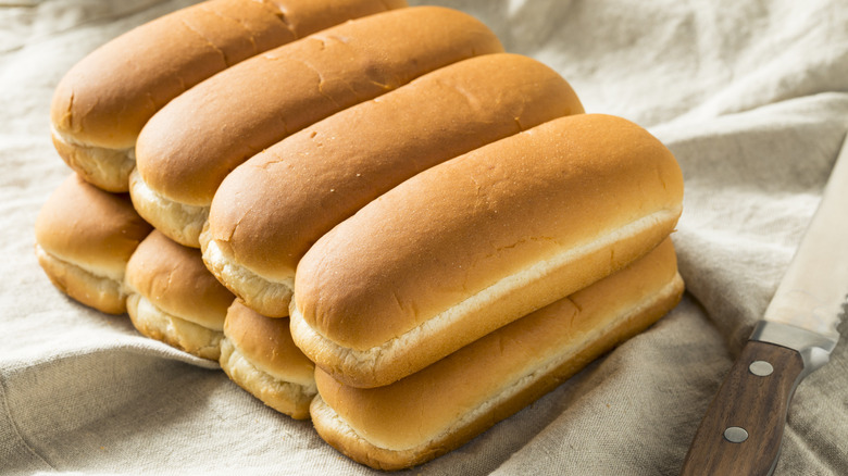 Hot dog buns on white cloth with knife