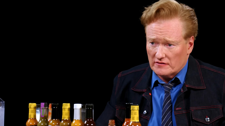 Conan O'Brien sitting in front of hot wing sauces